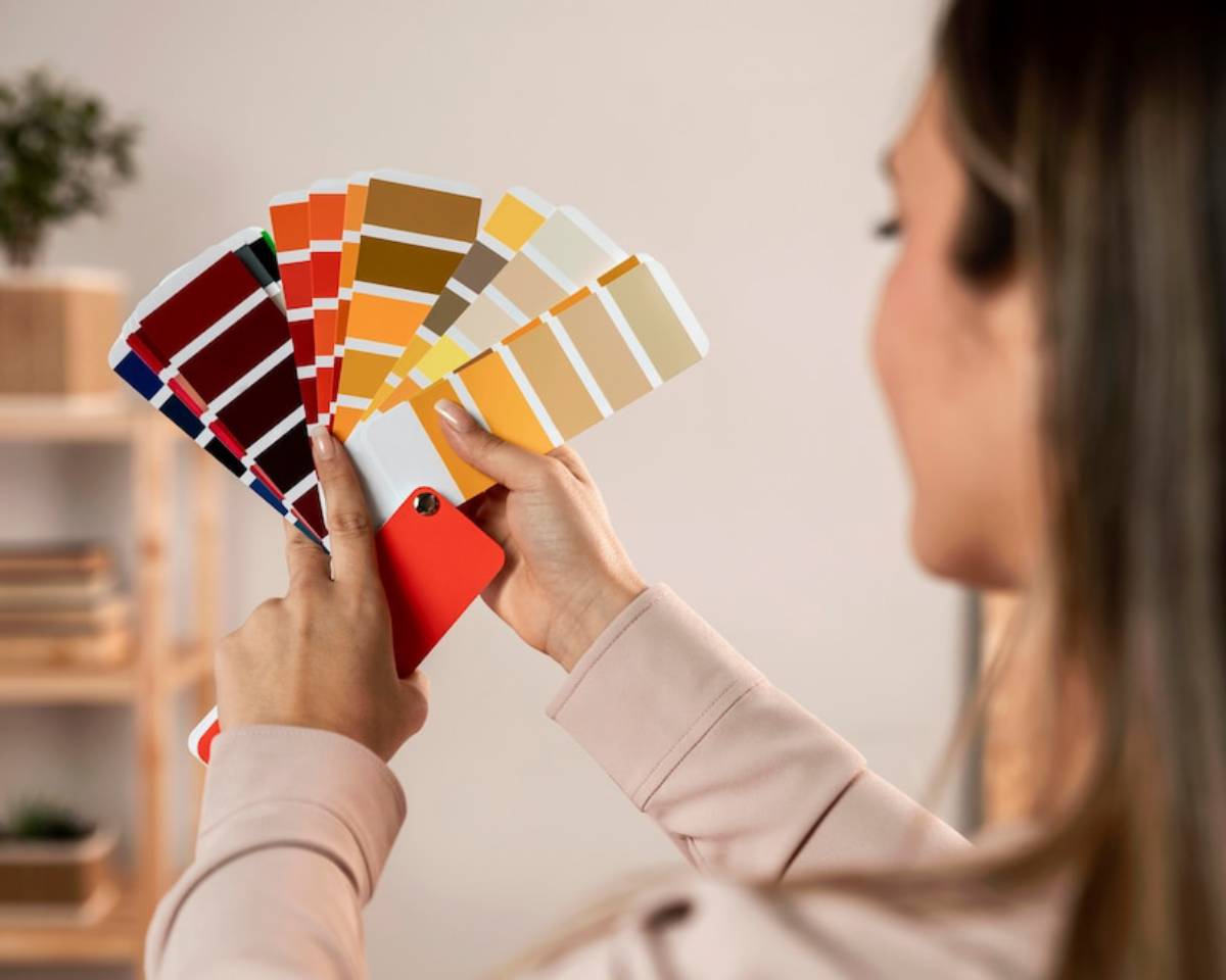 Woman examining multiple color swatches for selection in an interior setting.