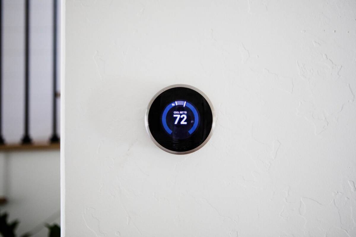 Digital thermostat displaying 72 degrees on a textured white wall.