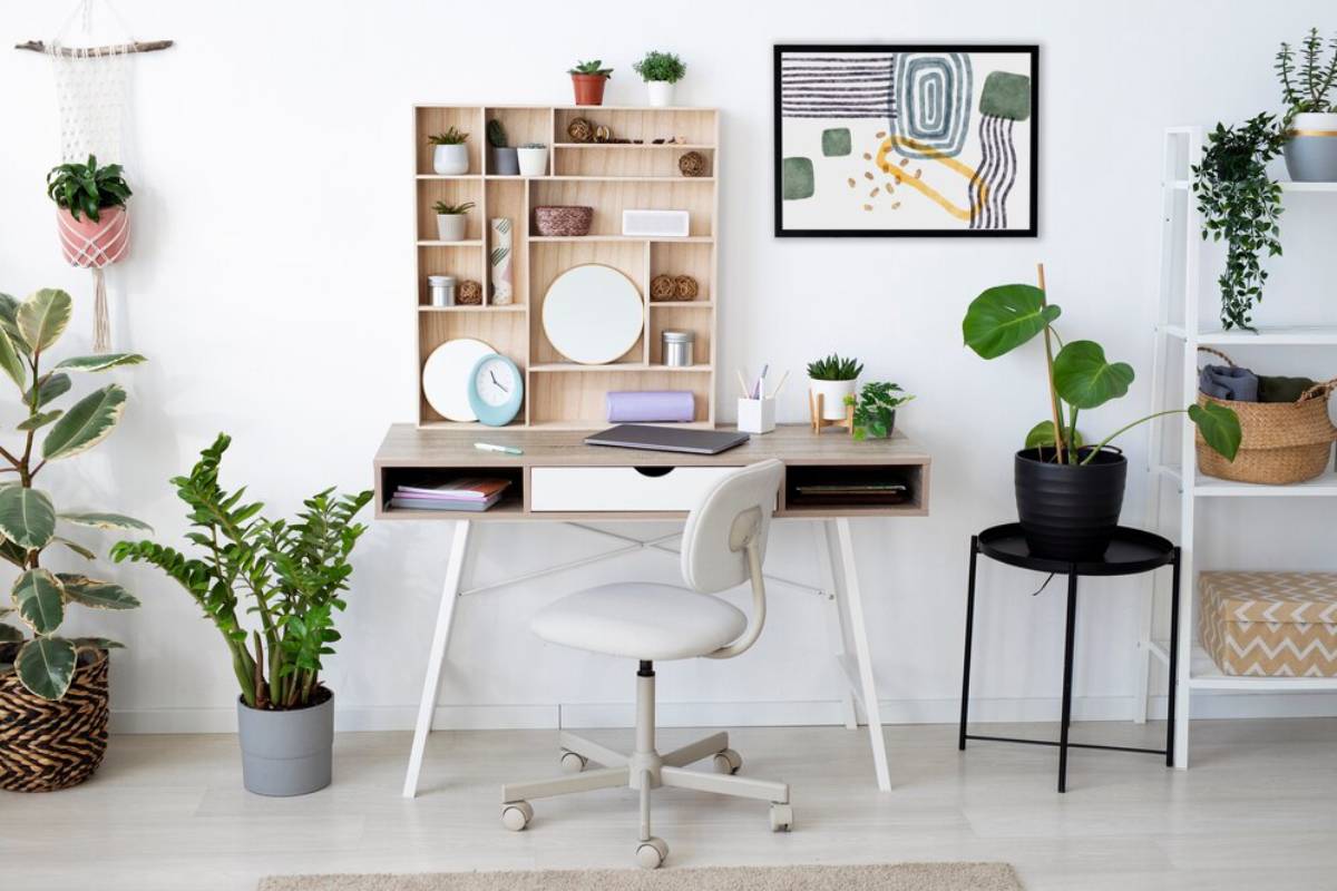 Modern home office with desk, chair, shelving full of plants and decor, and abstract wall art.