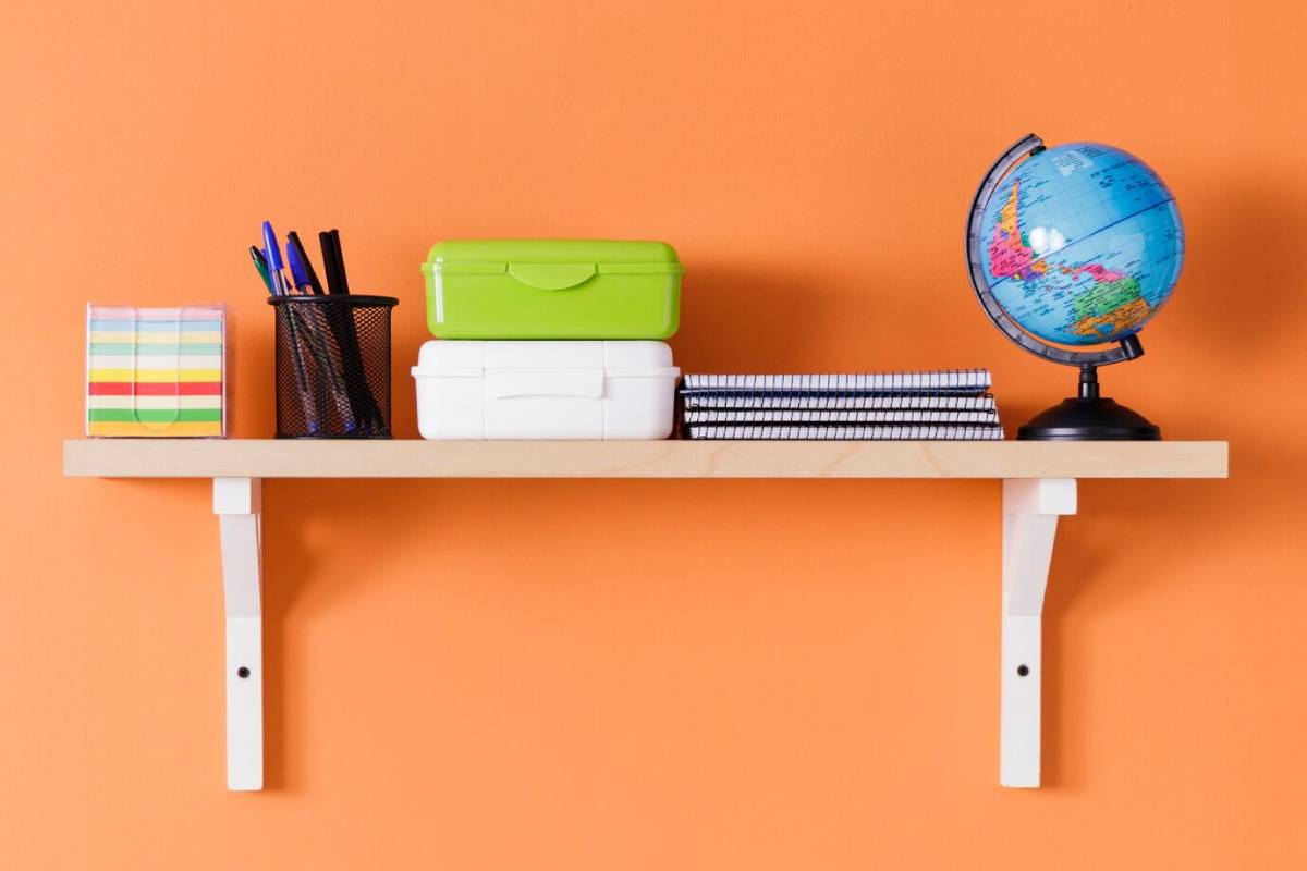 A shelf displaying various school supplies, including notebooks, pens, and markers, organized neatly.
