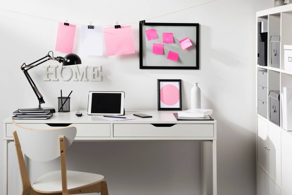 A white desk with a chair and a laptop, creating a minimalist workspace setup.