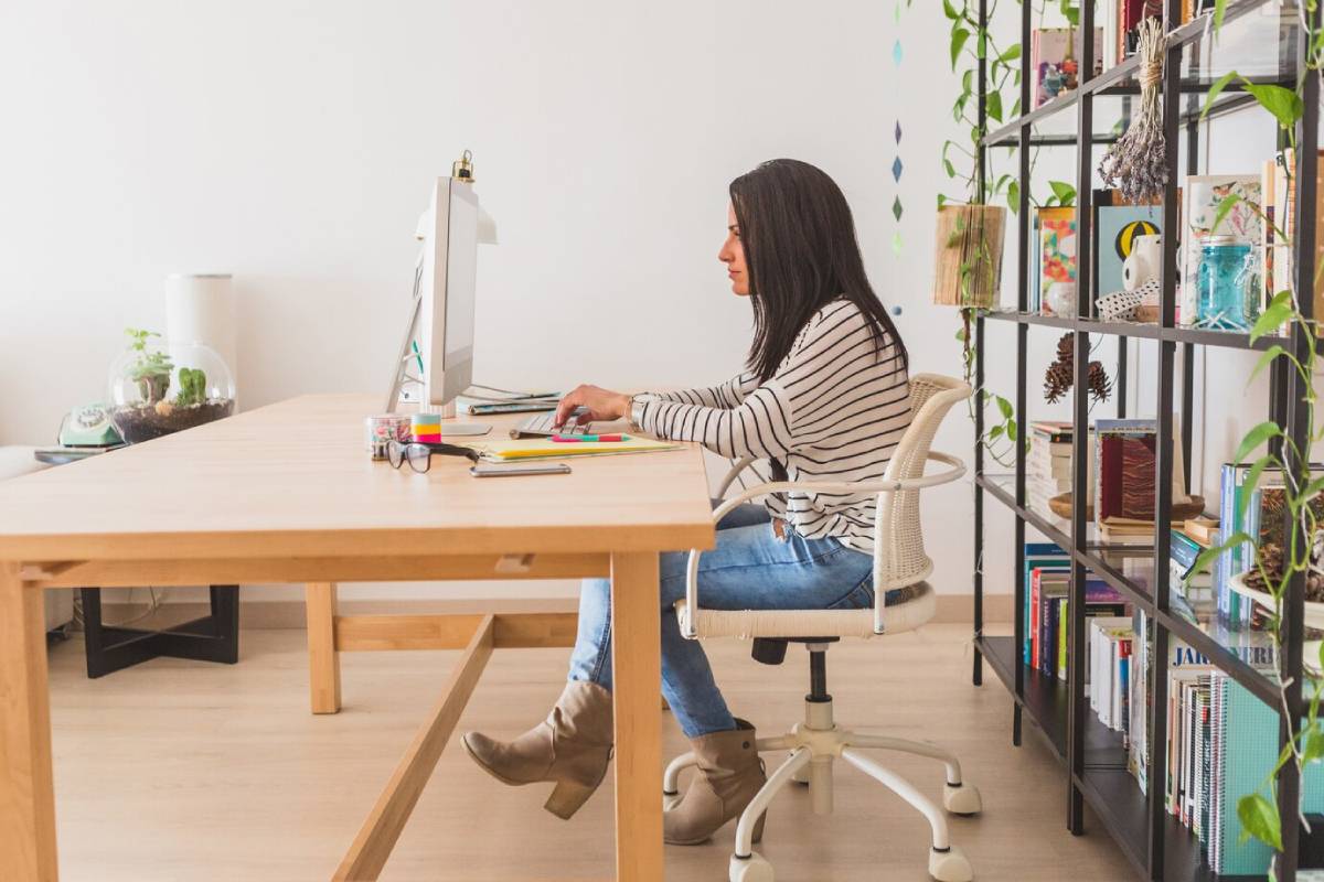 A woman seated at a desk, focused on her work at a computer.