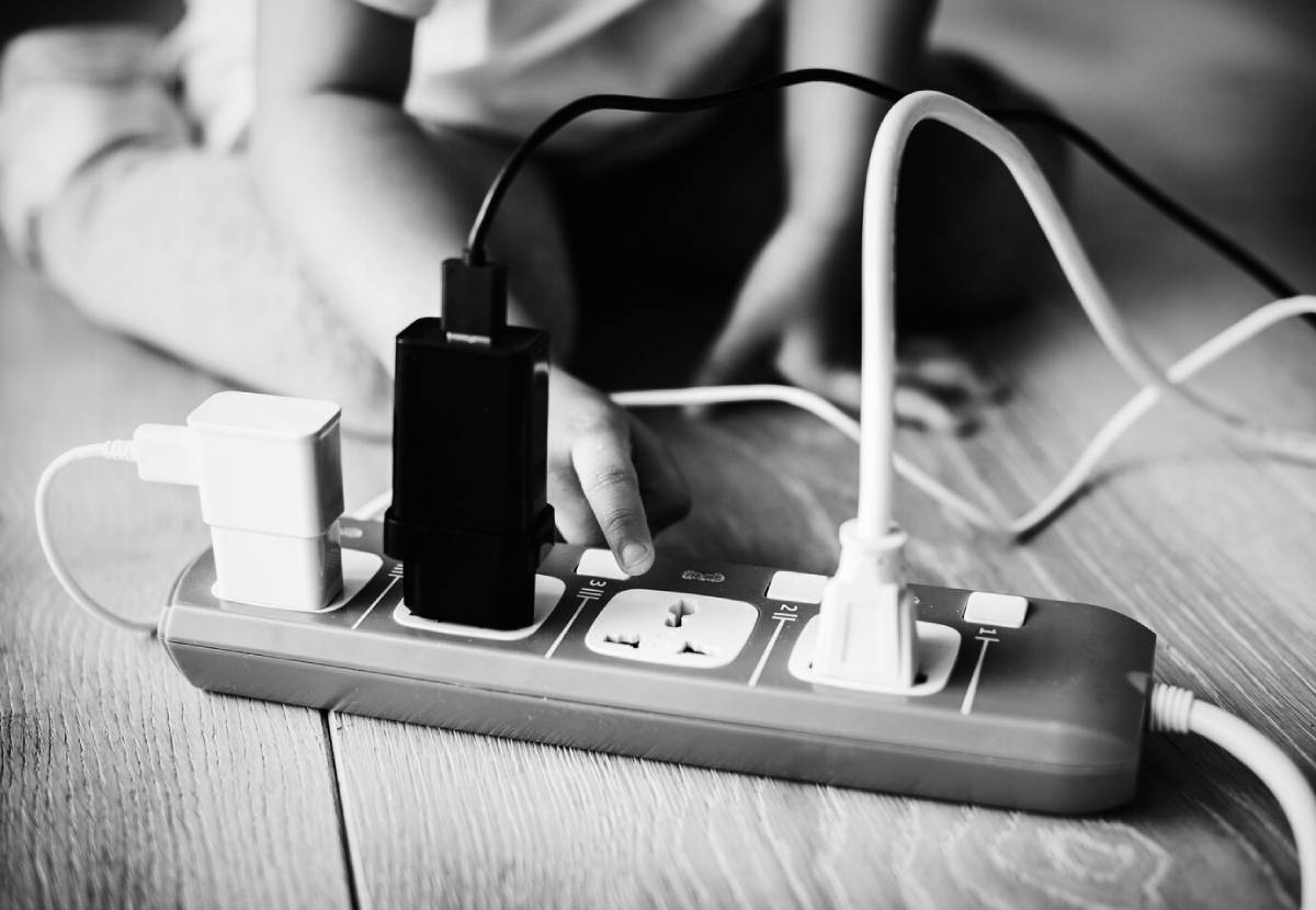 A child is playing with a power strip, exploring its buttons and cords in a safe indoor environment.
